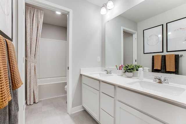 bathroom with double vanity, a sink, and toilet