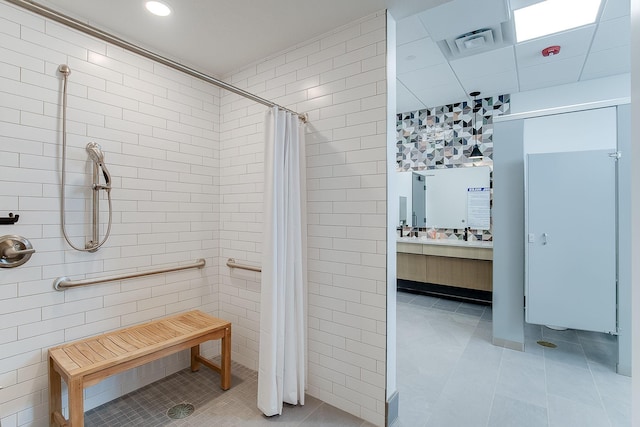 full bath with tile patterned flooring, vanity, visible vents, tile walls, and a stall shower