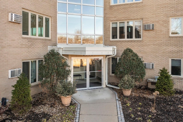 view of exterior entry featuring brick siding and a patio