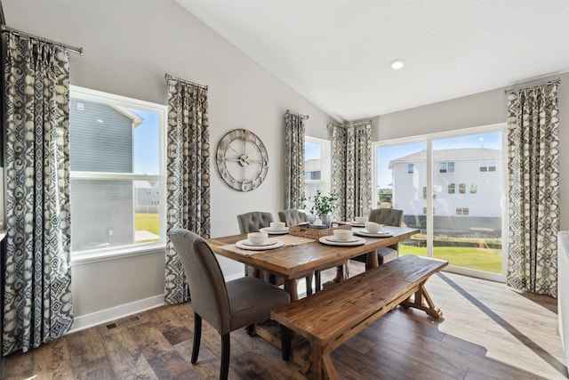 dining room with lofted ceiling, wood finished floors, visible vents, and baseboards