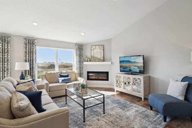 living area with recessed lighting, vaulted ceiling, dark wood-type flooring, and a glass covered fireplace