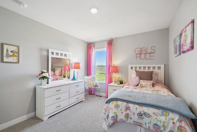 bedroom featuring light carpet, baseboards, and a textured ceiling