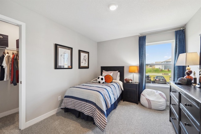 bedroom featuring a closet, light carpet, a spacious closet, and baseboards