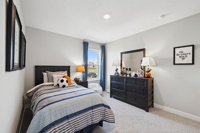 bedroom featuring light colored carpet, a textured ceiling, and baseboards