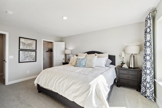 bedroom featuring baseboards, a spacious closet, and light colored carpet