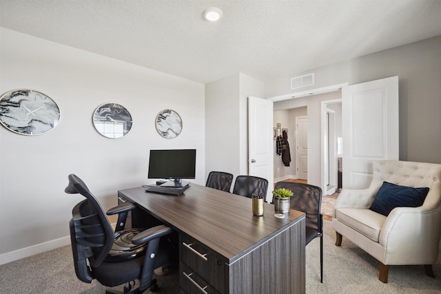 office space featuring visible vents, light carpet, baseboards, and a textured ceiling