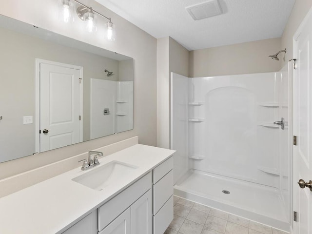 full bath featuring tile patterned flooring, visible vents, vanity, and walk in shower