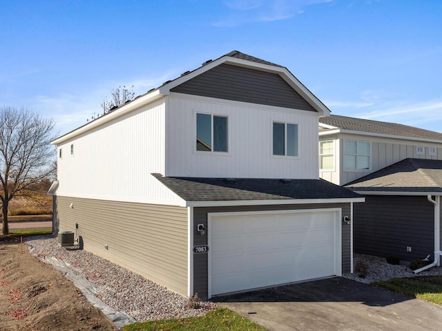 view of front of property featuring aphalt driveway, cooling unit, roof with shingles, and an attached garage