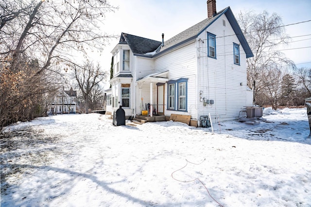 snow covered back of property with a chimney