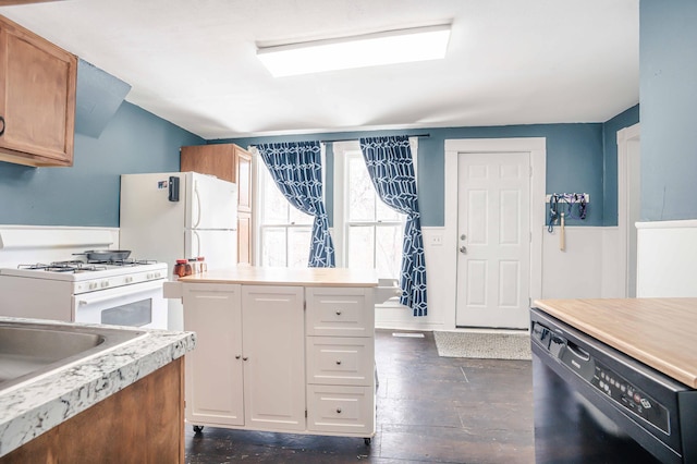 kitchen featuring brown cabinets, white appliances, light countertops, and a wainscoted wall