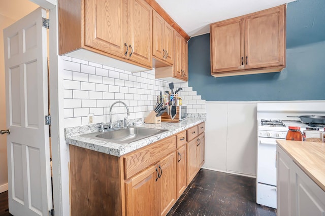 kitchen with a sink, white gas stove, light countertops, and dark wood-style floors