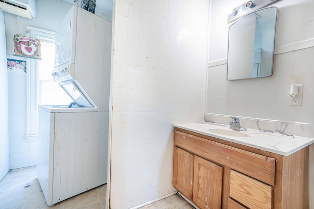 bathroom with tile walls, tile patterned floors, vanity, and stacked washer / drying machine