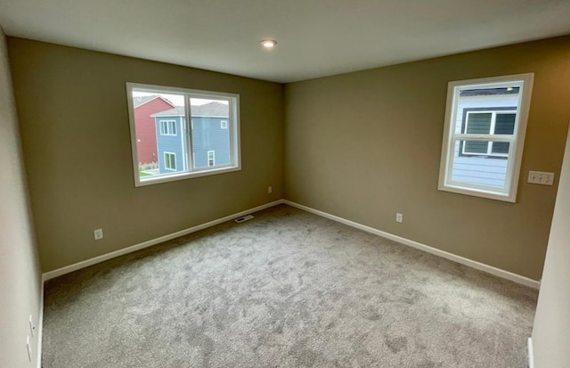 carpeted spare room featuring visible vents and baseboards