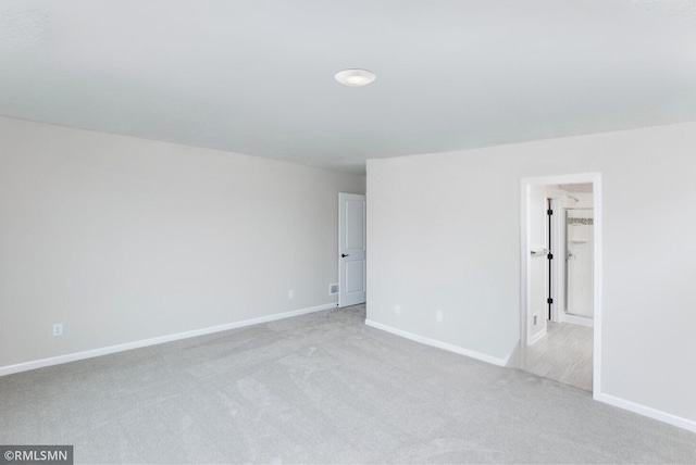 empty room featuring light carpet and baseboards