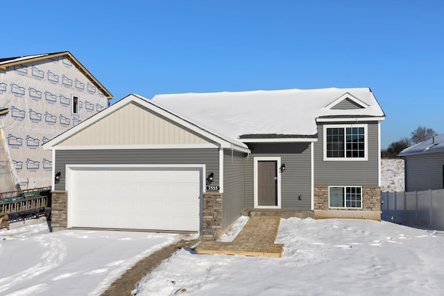 view of front of property with a garage, stone siding, and fence