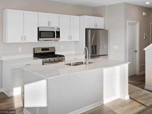 kitchen featuring an island with sink, appliances with stainless steel finishes, light wood-style floors, white cabinetry, and a sink