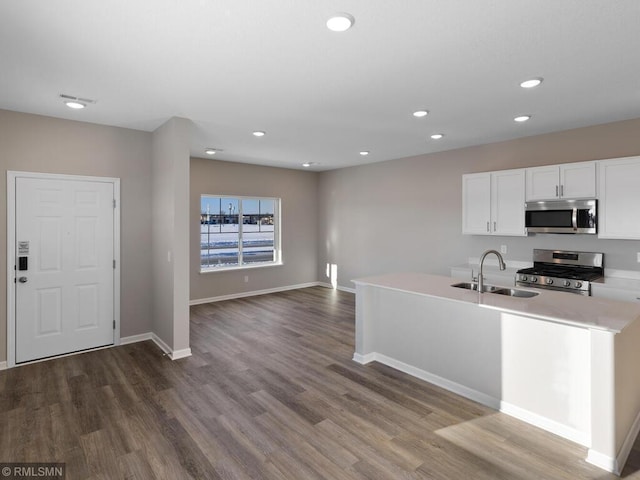 kitchen featuring dark wood-style flooring, light countertops, appliances with stainless steel finishes, white cabinetry, and a sink