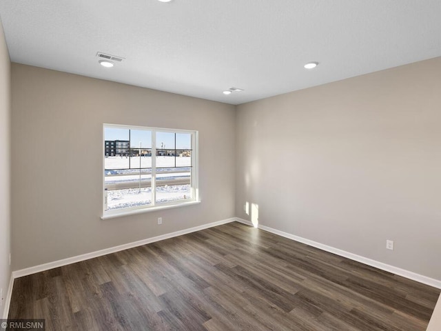 spare room with baseboards, visible vents, dark wood-style flooring, and recessed lighting