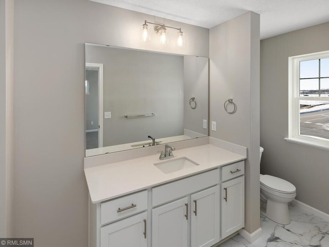 bathroom with toilet, marble finish floor, vanity, and baseboards