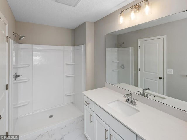 bathroom featuring a shower, marble finish floor, vanity, and a textured ceiling