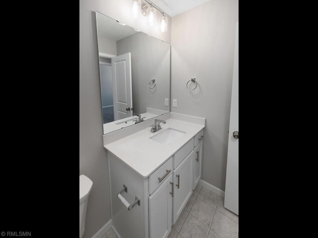 half bathroom featuring toilet, vanity, baseboards, and tile patterned floors