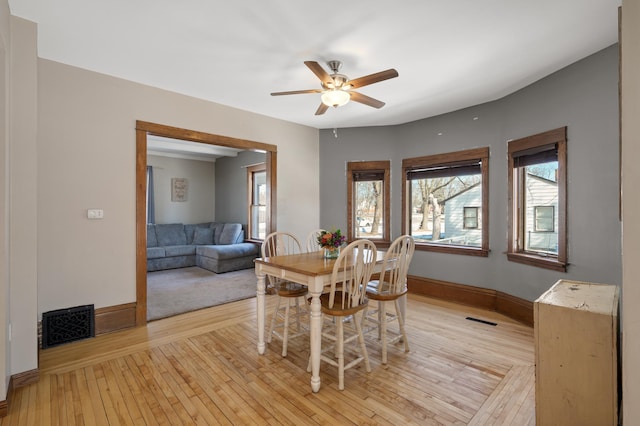 dining room featuring light wood finished floors, visible vents, and baseboards