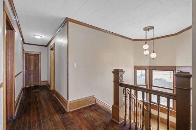 hall featuring an upstairs landing, ornamental molding, baseboards, and wood-type flooring