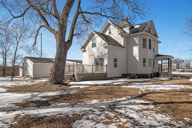 view of snowy exterior featuring an outdoor structure and a deck