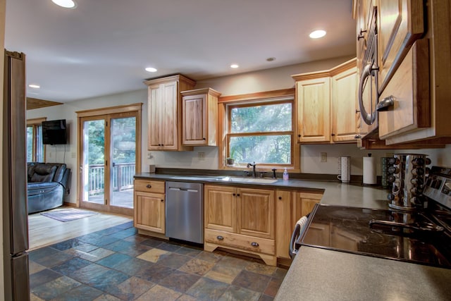 kitchen with dark countertops, stone finish floor, stainless steel appliances, a sink, and recessed lighting