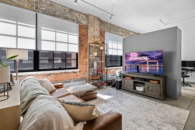 living area featuring brick wall, finished concrete floors, and track lighting