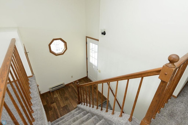 stairway featuring a baseboard radiator, wood finished floors, and a towering ceiling