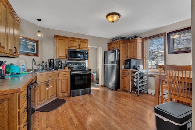 kitchen featuring electric range, a sink, light countertops, freestanding refrigerator, and pendant lighting