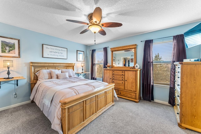 bedroom with multiple windows, baseboards, a textured ceiling, and light colored carpet