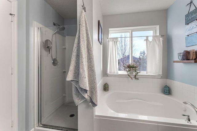 full bathroom with a shower stall and a bath