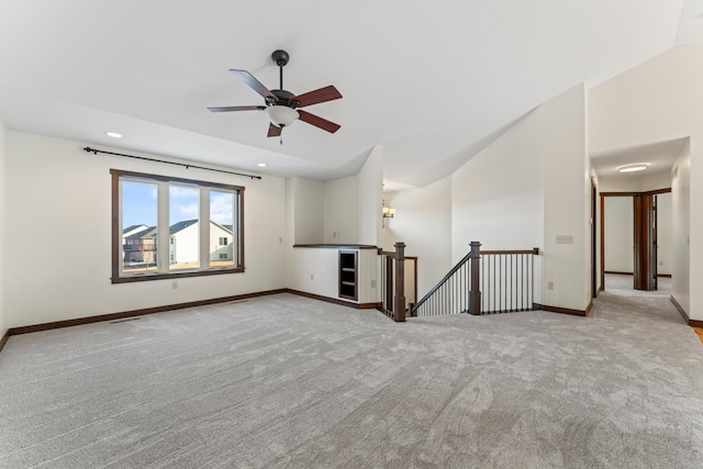 spare room featuring lofted ceiling, light carpet, baseboards, and recessed lighting