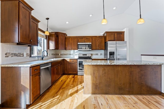 kitchen featuring hanging light fixtures, a kitchen island, appliances with stainless steel finishes, and a sink