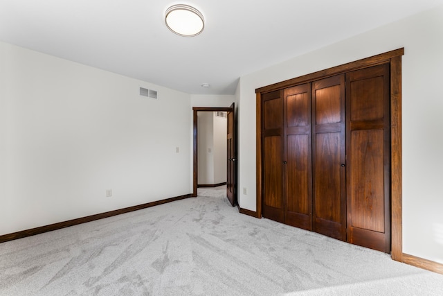 unfurnished bedroom featuring a closet, visible vents, light carpet, and baseboards