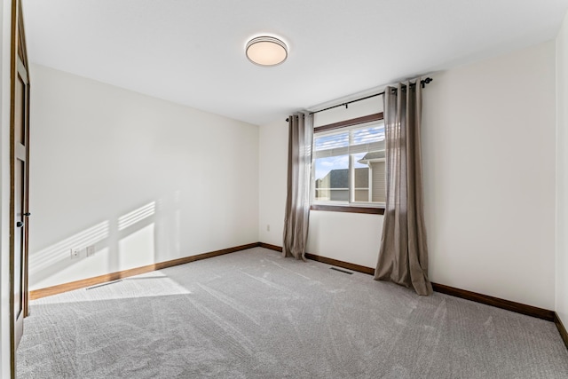 spare room with light colored carpet, visible vents, and baseboards