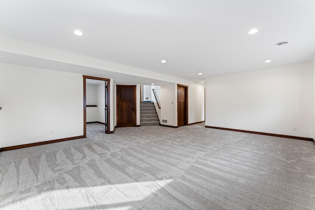 empty room with recessed lighting, light colored carpet, baseboards, and stairs