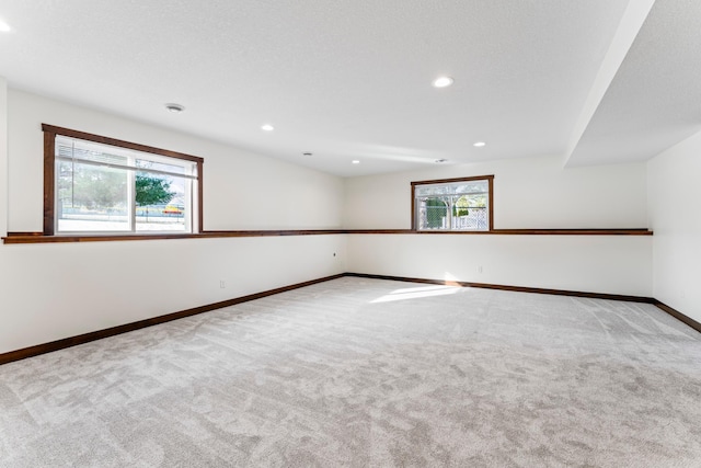 empty room featuring light carpet, baseboards, and recessed lighting