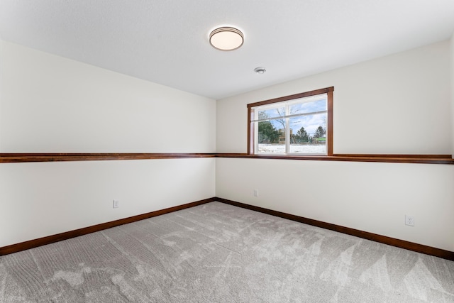 unfurnished room featuring light carpet and baseboards