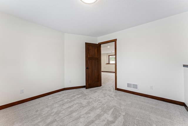 unfurnished room with light carpet, visible vents, and baseboards