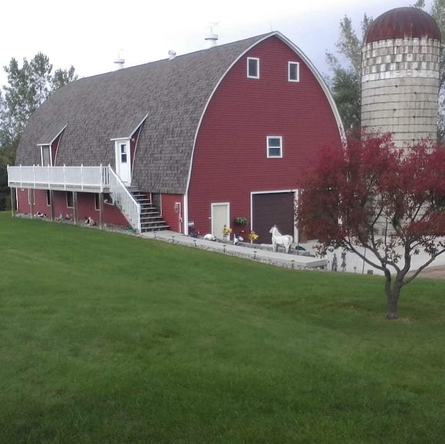 rear view of property with a shingled roof, stairway, a lawn, and a gambrel roof