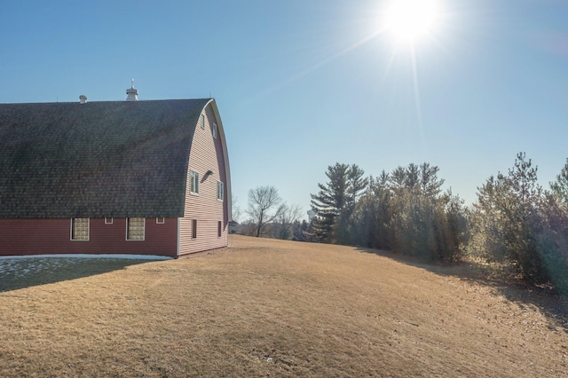 view of property exterior featuring a yard, roof with shingles, and a gambrel roof