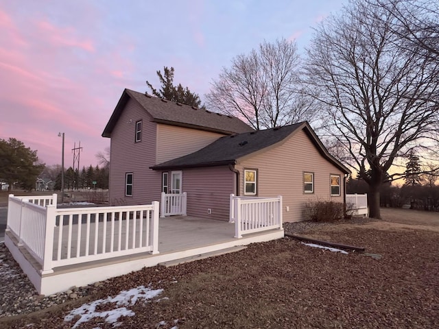 rear view of house with a deck and roof with shingles