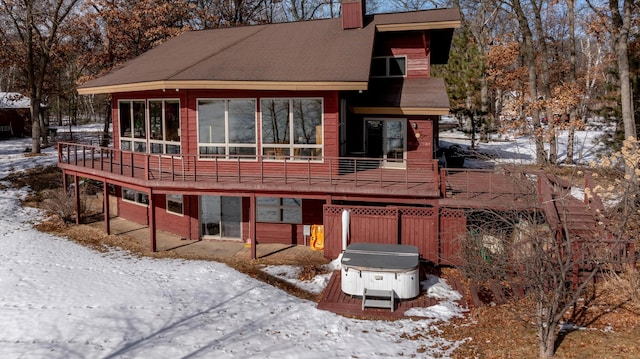 snow covered property with a chimney and a wooden deck