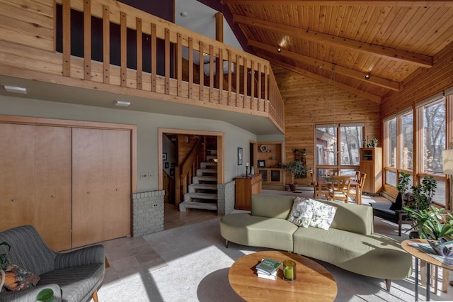 living area featuring wooden walls, wood ceiling, stairway, high vaulted ceiling, and beam ceiling