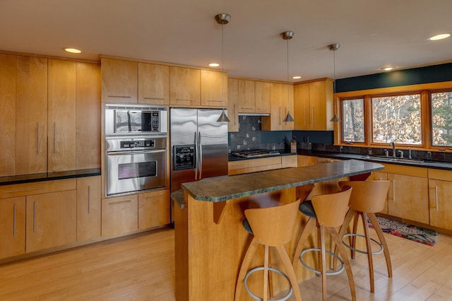 kitchen with appliances with stainless steel finishes, dark countertops, decorative light fixtures, and a sink