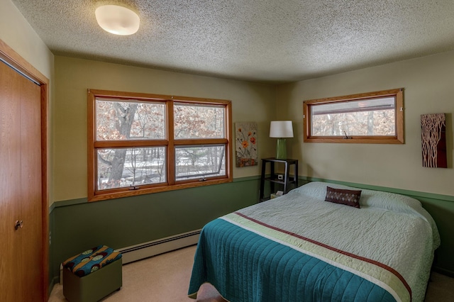 carpeted bedroom with a closet, a textured ceiling, and baseboard heating