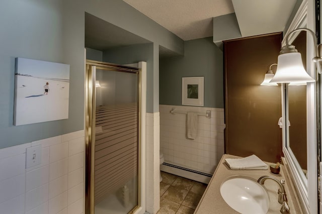 full bath featuring tile walls, baseboard heating, a stall shower, a textured ceiling, and tile patterned floors